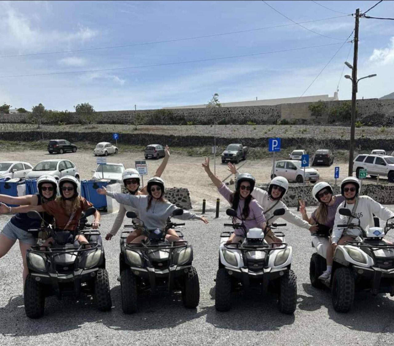 Riders posing with ATVs at Santorini lighthouse viewpoint